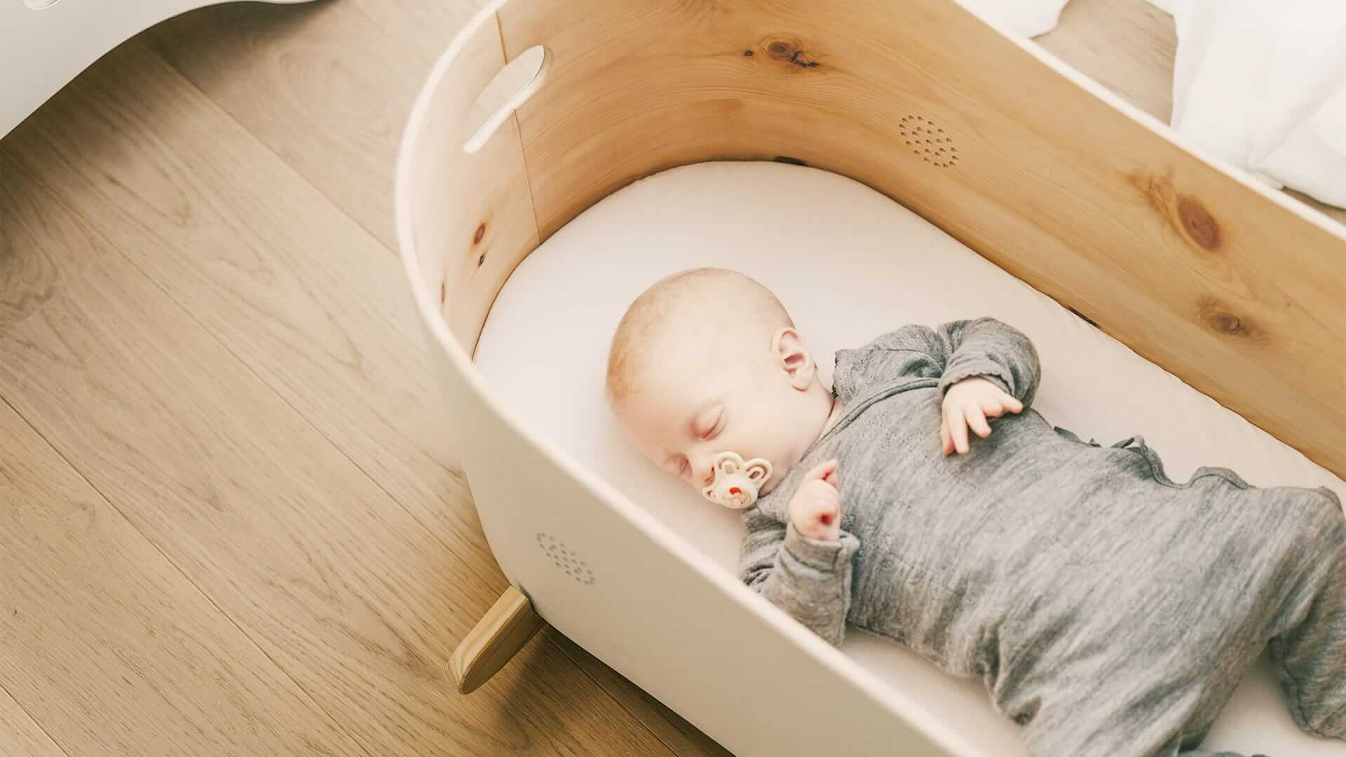 Ein schlafendes Baby in einem handgefertigten Zirben-Babybett